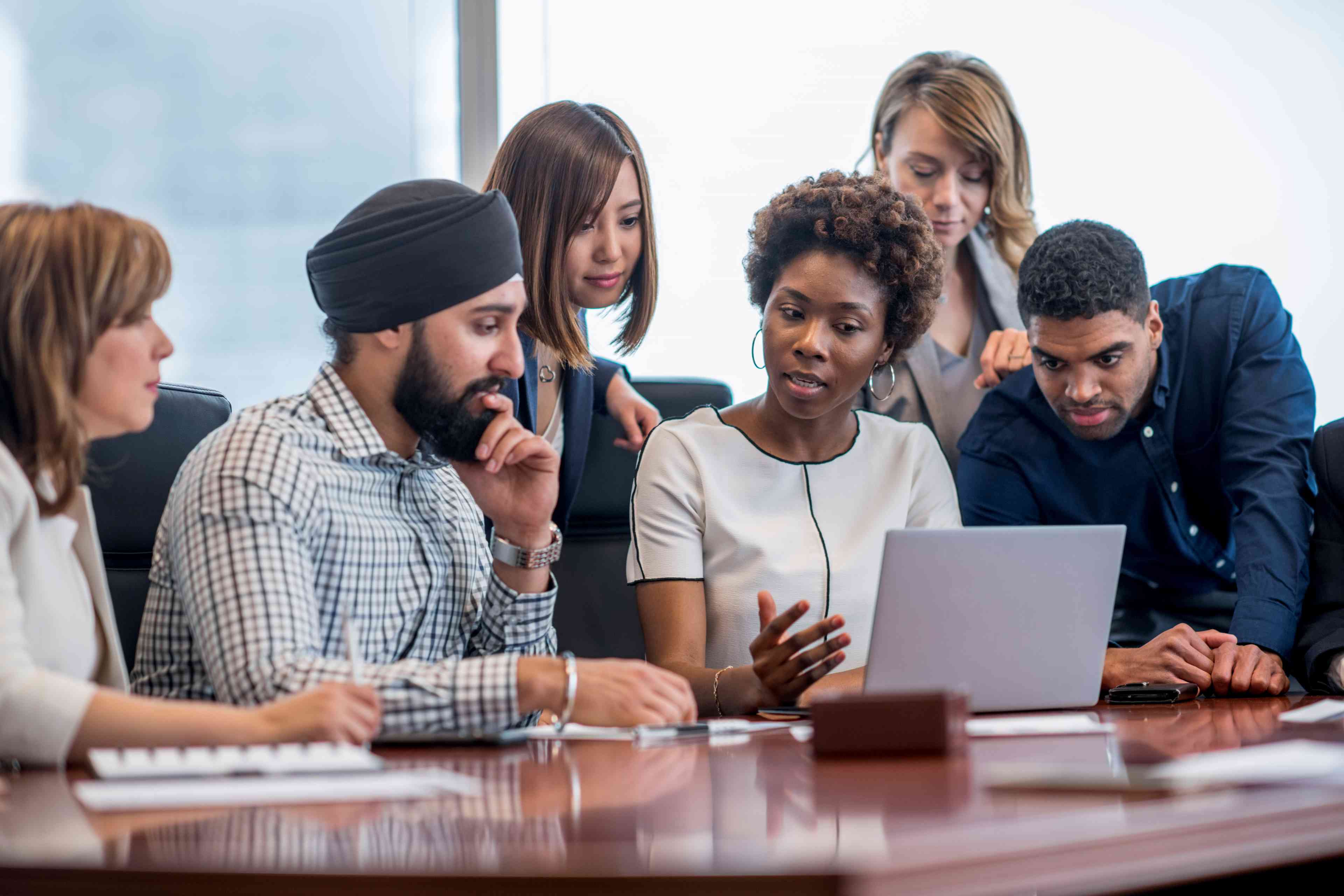 Diverse team collaborating around a laptop